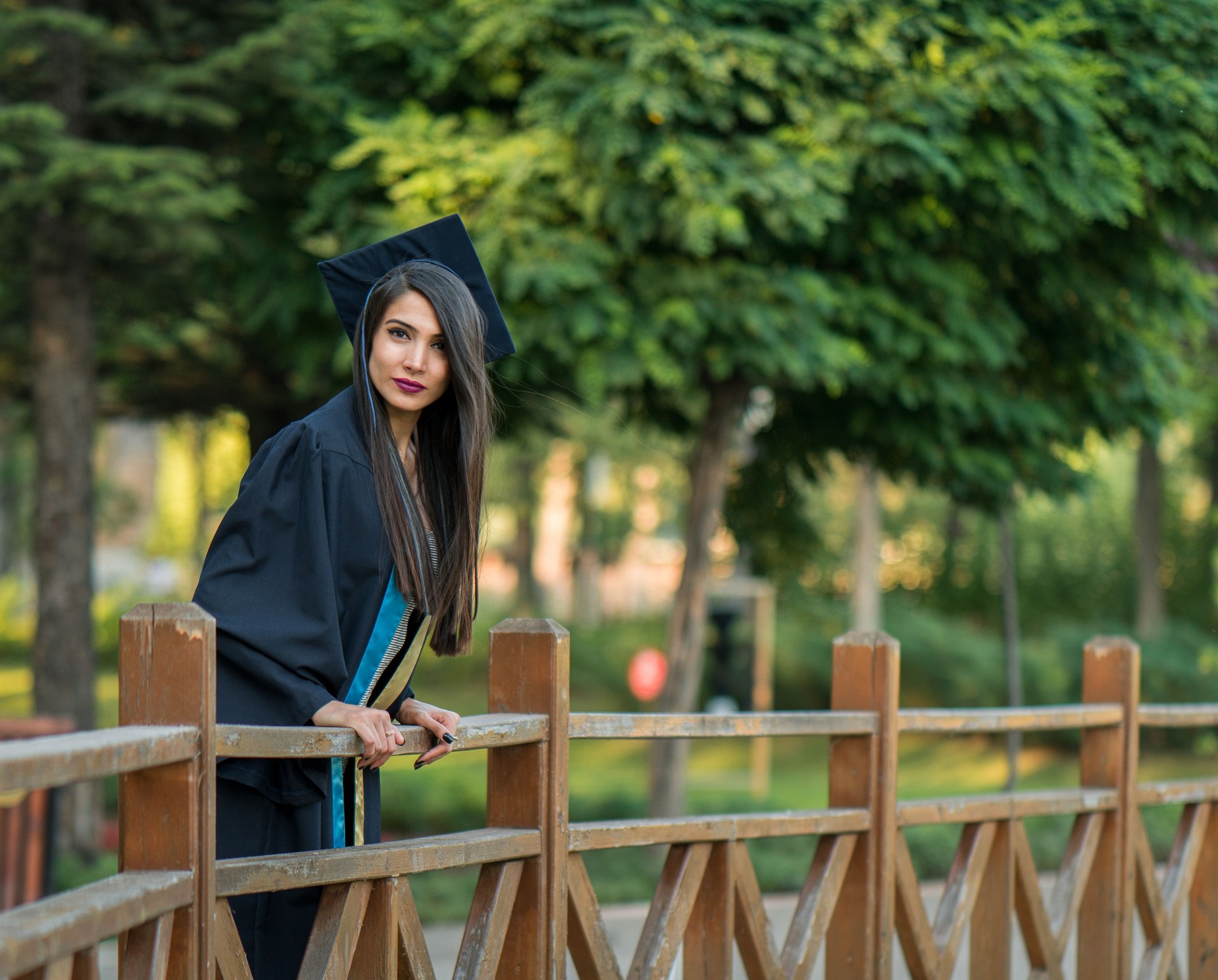 Woman taking a lot of different graduation photos in a beautiful botanical park.